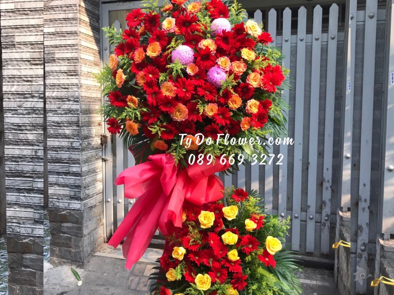 KCM01241261 KỆ HOA CHÚC MỪNG thiết kế tone màu đỏ-cam chủ đạo Hoa Hồng Cam Spirit Roses, Đồng Tiền Đỏ, điểm nhấn Cúc Mẫu Đơn Hồng