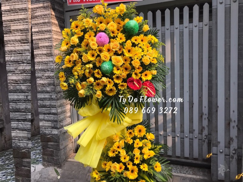 KCM01241262 KỆ HOA CHÚC MỪNG thiết kế tone màu vàng chủ đạo Hoa Hồng Vàng, Đồng Tiền Vàng, điểm nhấn Cúc Mẫu Đơn Xanh-Hồng