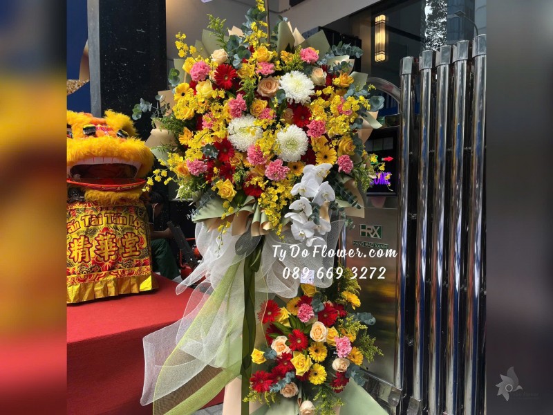 KCM01252 KỆ HOA CHÚC MỪNG Thiết kế tông màu đa sắc rực rỡ , chủ đạo Hoa Lan Vũ Nữ, Cẩm Chướng Phăng Hồng, Hoa Lan Hồ Điệp, Hoa Hồng Đỏ