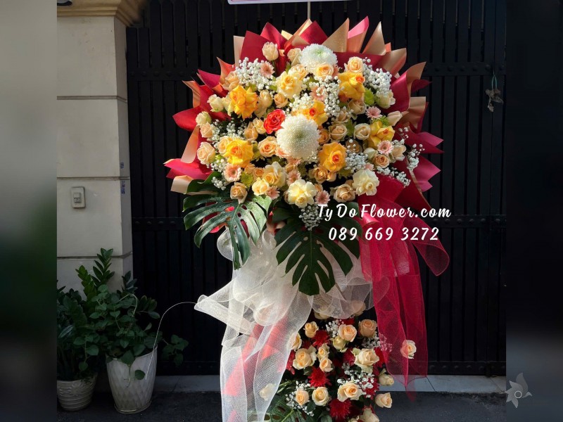 KCM01253 KỆ HOA CHÚC MỪNG Thiết kế tông màu vàng cam, chủ đạo Hoa Hồng Vàng Gold Victor, cam trứng, Lá Trầu Bà Nam Mỹ