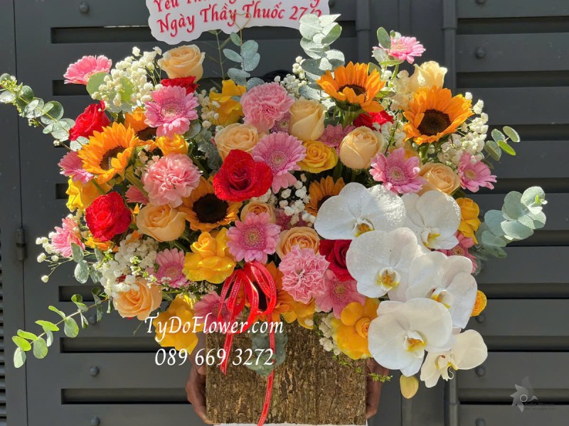 G0125169 GIỎ HOA CHÚC MỪNG NGÀY THẦY THUỐC VN Thiết kế tông màu đỏ cam, chủ đạo Hoa Hồng Đỏ Cam, Hướng Dương, Lan Hồ Điệp Trắng, Đồng Tiền Mini Hồng