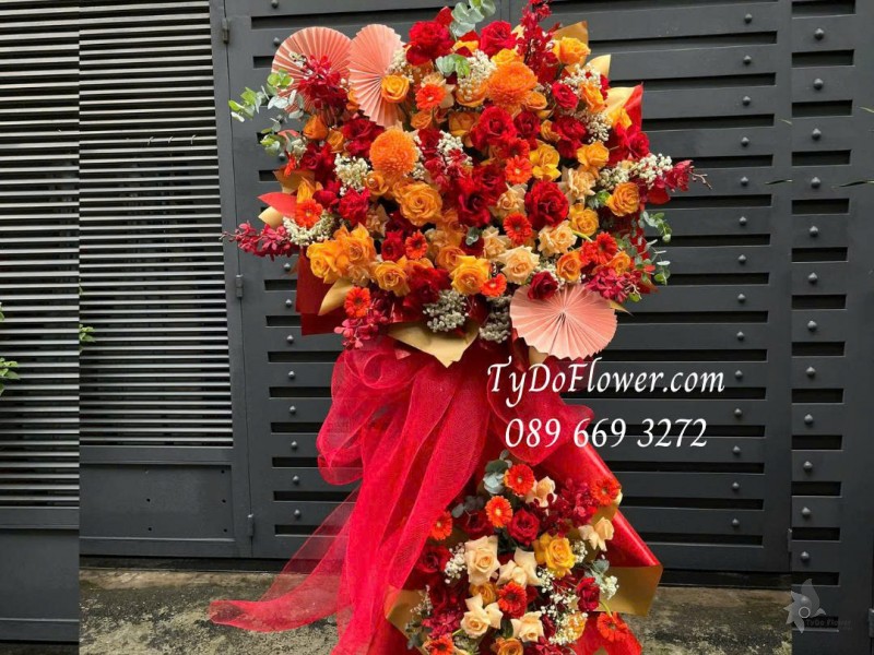 KCM0725503 KỆ HOA CHÚC MỪNG Thiết kế gam màu đỏ cam, chủ đạo hoa hồng đỏ, hoa hồng cam party, đồng tiền