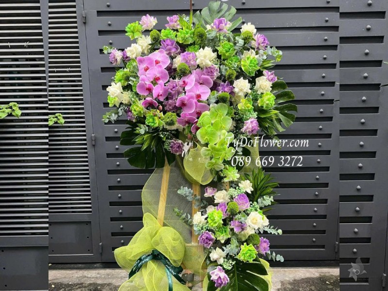 KCM0825611 KỆ HOA CHÚC MỪNG Thiết kế gam màu tím xanh bơ, chủ đạo hoa hồng, lan hồ điệp, wicky, lá trầu bà nam mỹ