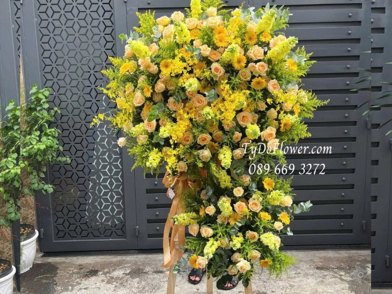 KCM0825614 KỆ HOA CHÚC MỪNG Thiết kế gam màu vàng cam, chủ đạo hoa hồng cam, lan vũ nữ, mõm sói vàng