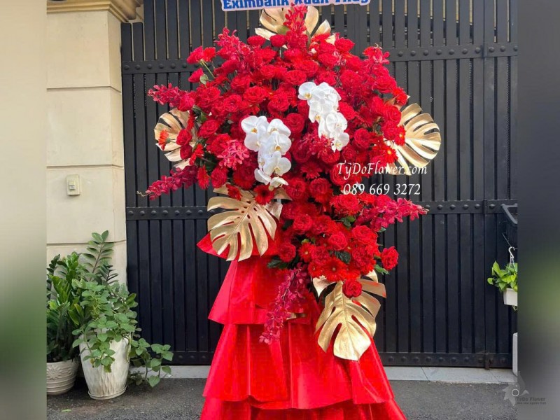 KCM0825647 KỆ HOA CHÚC MỪNG KHAI TRƯƠNG Thiết kế hoa hồng đỏ Ohara Red Rose, Lan Hồ Điệp, Lá Trầu Bà Nam Mỹ