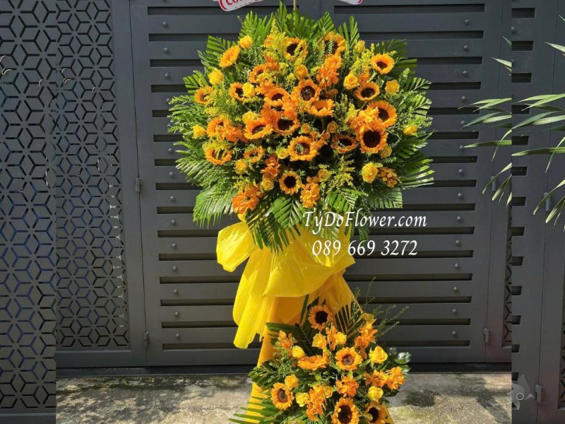 KCM0925723 KỆ HOA CHÚC MỪNG KỶ NIỆM THÀNH LẬP Thiết kế hoa hồng vàng Gold, hoa hướng dương, lan Mokara