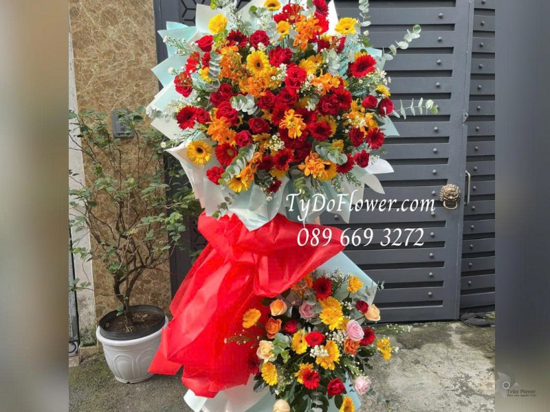 KCM0126030 KỆ HOA CHÚC MỪNG KỶ NIỆM NGÀY THÀNH LẬP Thiết kế tông màu đỏ vàng, hoa hồng, đồng tiền, lan mokara