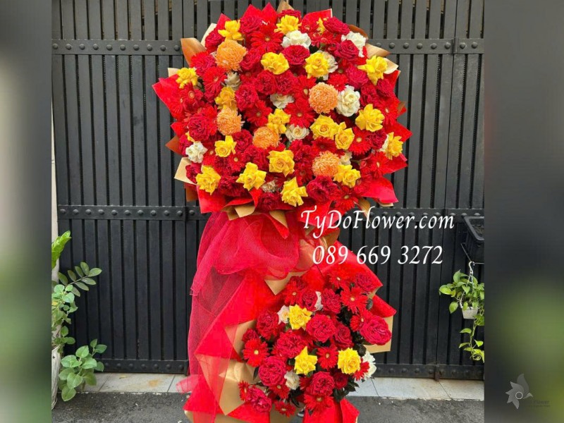 KCM0226120 KỆ HOA 02 TẦNG CHÚC MỪNG KHAI TRƯƠNG Thiết kế tông màu đỏ vàng cam, chủ đạo hoa hồng, đồng tiền, cúc mẫu đơn