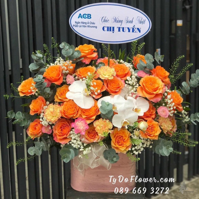 G0623757 GIỎ HOA CHÚC MỪNG SINH NHẬT thiết kế hoa hồng Cam Spirit, Lan Hồ Điệp trắng, cẩm chướng cam, baby trắng, lá bạc