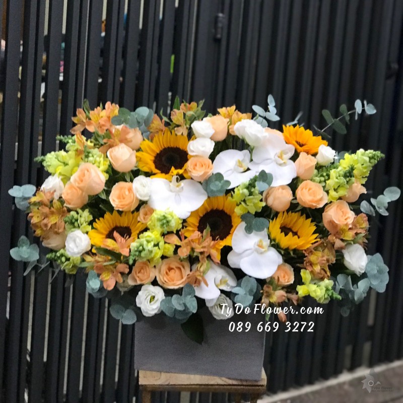 G0823909 GIỎ HOA CHÚC MỪNG thiết kế hoa hướng dương, hoa hồng cam, mõm sói vàng, cát tường trắng, lan Mokara vàng điểm nhấn Hoa Lan Hồ Điệp Trắng