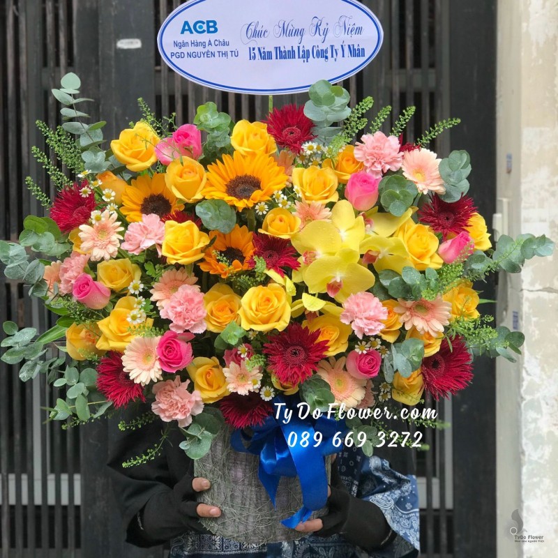 G0823959 GIỎ HOA CHÚC MỪNG KỶ NIỆM THÀNH LẬP CÔNG TY - thiết kế hoa hướng dương, hoa hồng vàng-hồng, cầm chướng hồng, đồng tiền đỏ-cam điểm nhấn Hoa Lan Hồ Điệp Vàng,