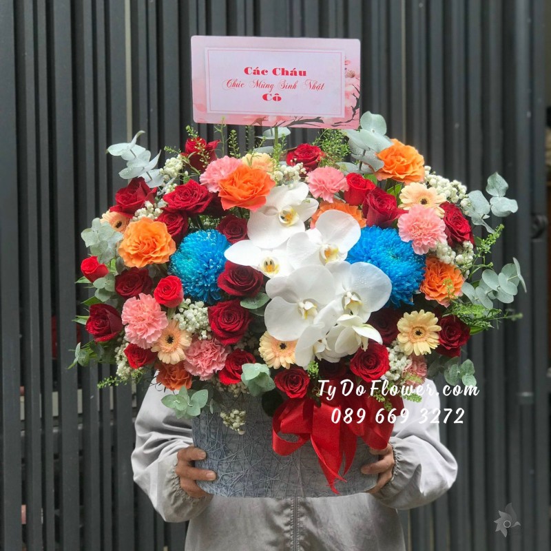 G10231054 GIỎ HOA CHÚC MỪNG SINH NHẬT - thiết kế Hoa Hồng Đỏ Ecuador, Cam Spirit Roses, Cẩm Chướng Hồng điểm nhấn Cúc Mẫu Đơn Xanh, Lan Hồ Điệp Trắng mix Đồng Tiền Mini Cam, Cỏ Đồng Tiền, Baby Trắng, Lá Bạc
