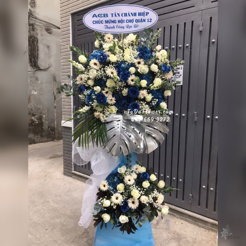 KCM01241294 KỆ HOA CHÚC MỪNG THÀNH CÔNG RỰC RỠ thiết kế tone màu trắng xanh, chủ đạo Hoa Hồng Xanh Dương