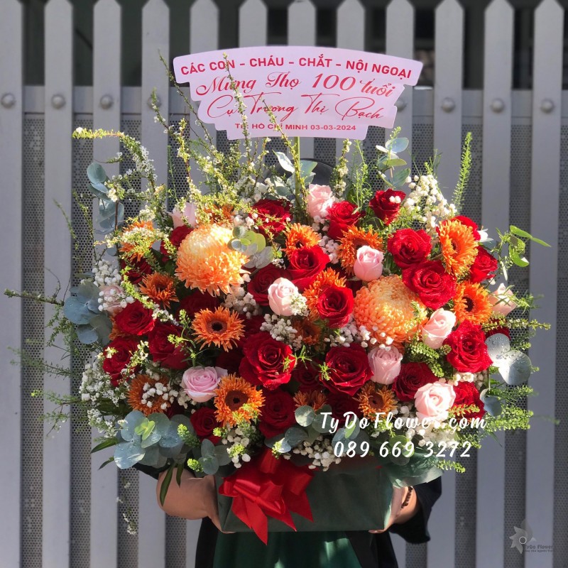 G03241397 GIỎ HOA MỪNG THỌ 100 TUỔI thiết kế tone màu đỏ cam, chủ đạo Hoa Hồng Đỏ Ecuador, Cúc Mẫu Đơn Cam