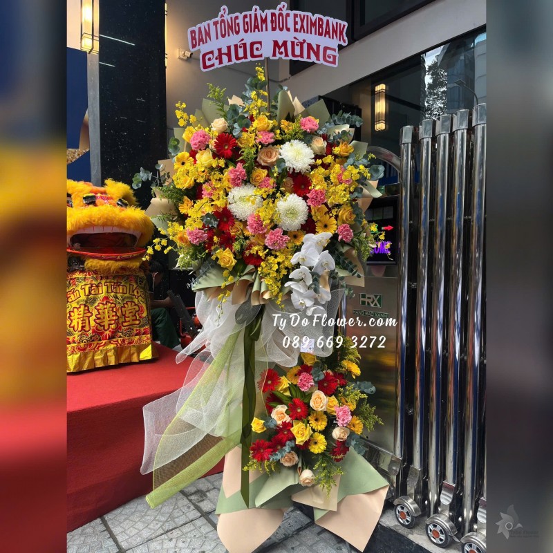 KCM01252 KỆ HOA CHÚC MỪNG Thiết kế tông màu đa sắc rực rỡ , chủ đạo Hoa Lan Vũ Nữ, Cẩm Chướng Phăng Hồng, Hoa Lan Hồ Điệp, Hoa Hồng Đỏ