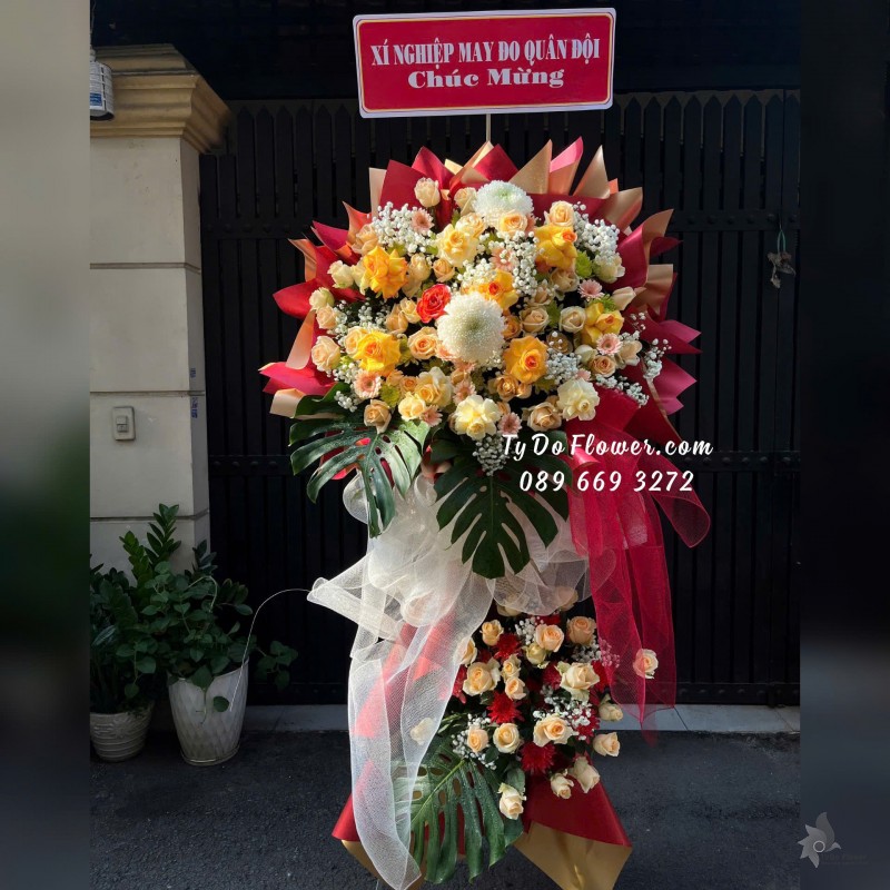 KCM01253 KỆ HOA CHÚC MỪNG Thiết kế tông màu vàng cam, chủ đạo Hoa Hồng Vàng Gold Victor, cam trứng, Lá Trầu Bà Nam Mỹ