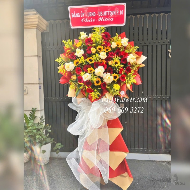 KCM012513 KỆ HOA CHÚC MỪNG Thiết kế tông màu đỏ vàng, chủ đạo Hoa Hồng Vàng Victor, Hướng Dương, Đồng Tiền