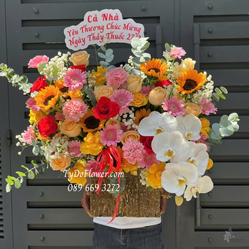 G0125169 GIỎ HOA CHÚC MỪNG NGÀY THẦY THUỐC VN Thiết kế tông màu đỏ cam, chủ đạo Hoa Hồng Đỏ Cam, Hướng Dương, Lan Hồ Điệp Trắng, Đồng Tiền Mini Hồng