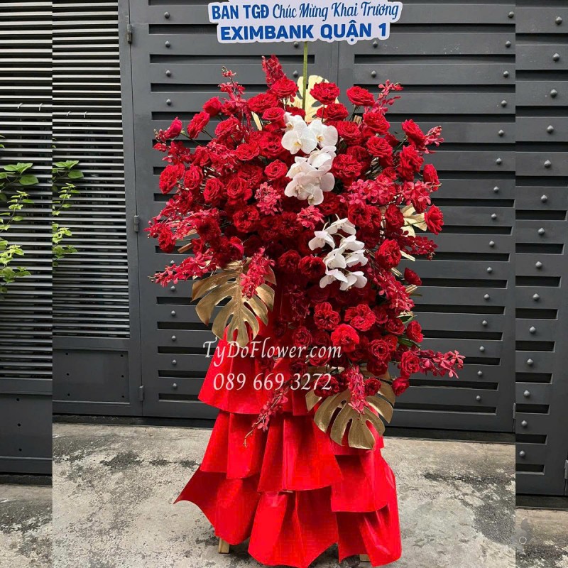 KCM0625491 KỆ HOA CHÚC MỪNG KHAI TRƯƠNG Thiết kế Hoa Hồng Đỏ Ohara Red Roses, Lan Đỏ Mokara, Lan Hồ Điệp, Lá Trầu Bà Nam Mỹ