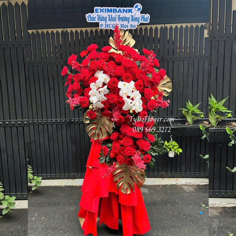 KCM0825618 KỆ HOA CHÚC MỪNG KHAI TRƯƠNG HỒNG PHÁT Thiết kế hoa hồng đỏ Ohara Red Rose, Lan Hồ Điệp, Lá Trầu Bà Nam Mỹ