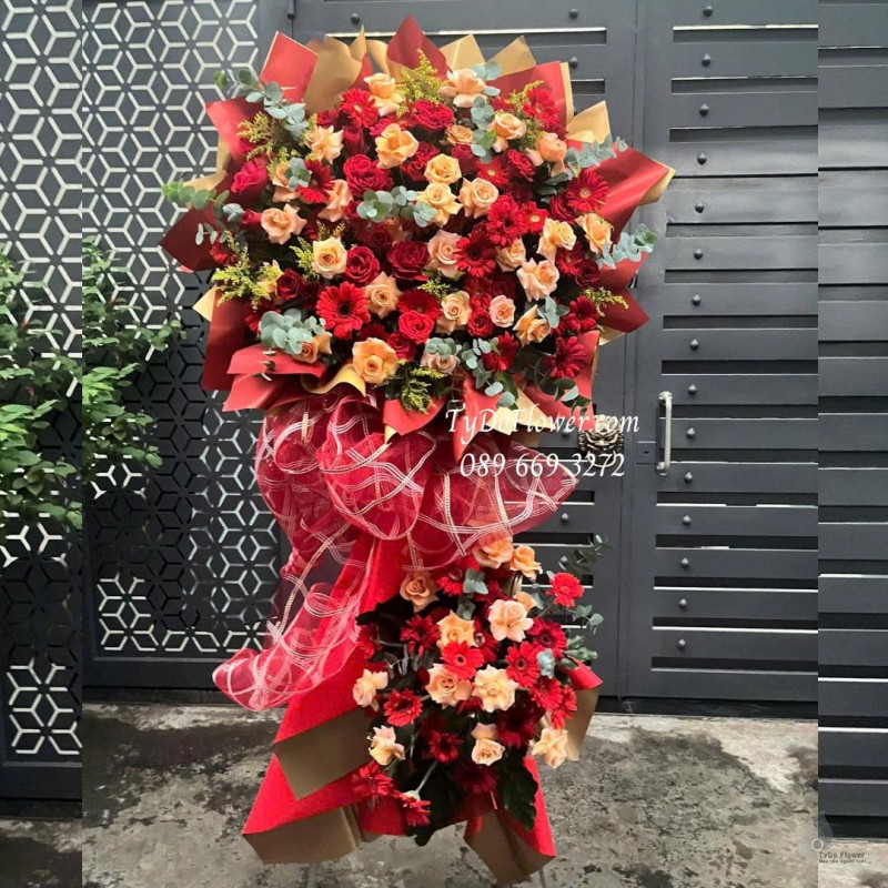 KCM0825622 KỆ HOA CHÚC MỪNG Thiết kế hoa hồng đỏ cam, đồng tiền đỏ, nền giấy mỹ thuật cao cấp