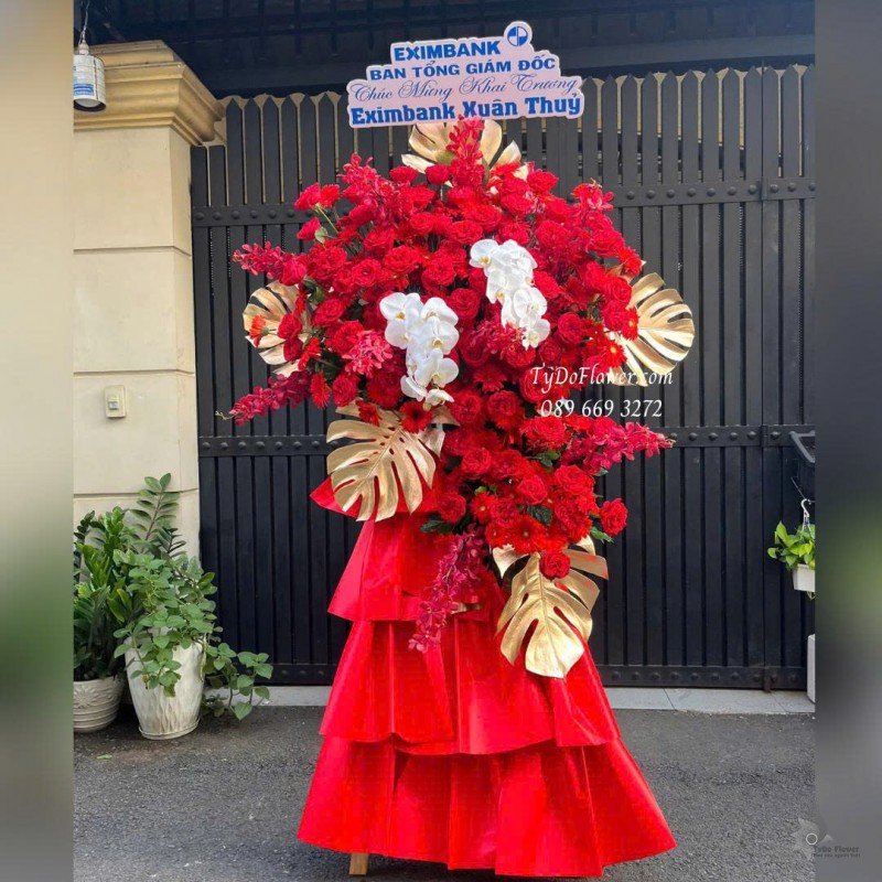 KCM0825647 KỆ HOA CHÚC MỪNG KHAI TRƯƠNG Thiết kế hoa hồng đỏ Ohara Red Rose, Lan Hồ Điệp, Lá Trầu Bà Nam Mỹ