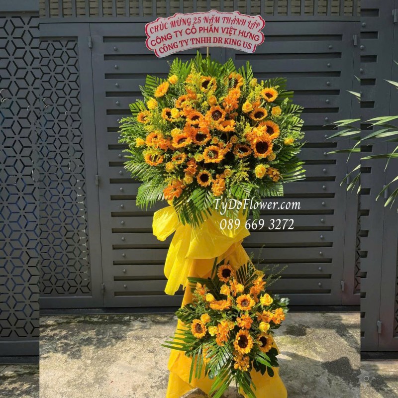 KCM0925723 KỆ HOA CHÚC MỪNG KỶ NIỆM THÀNH LẬP Thiết kế hoa hồng vàng Gold, hoa hướng dương, lan Mokara